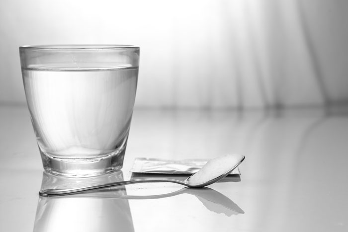 clear glass of water with powder substance on spoon